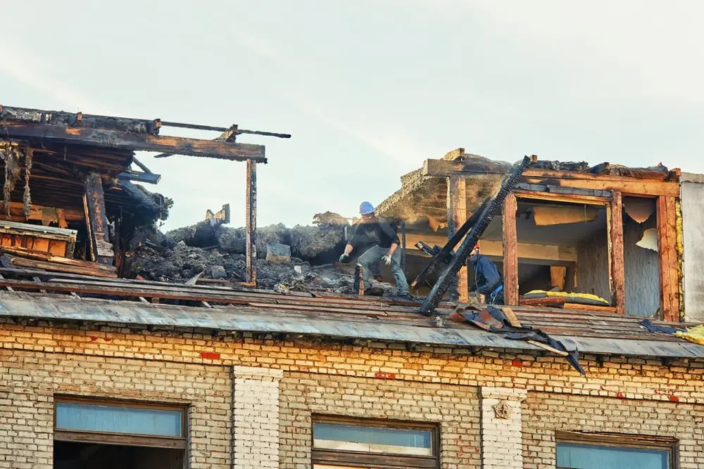 Worker inspecting fire-damaged building roof